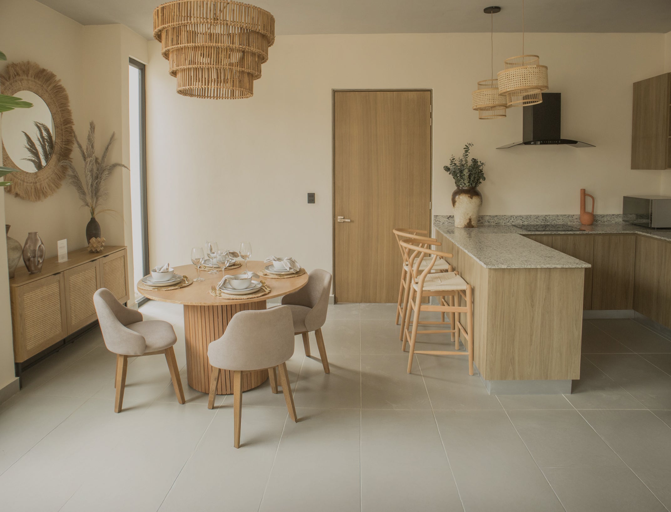 Comedor moderno para 4 personas con mesa redonda de madera, sillas tapizadas y bufetera de rejilla en espacio costero con lámparas colgantes | Prisma Muebles. Comedor moderno para 4 personas con mesa redonda de madera, sillas tapizadas y bufetera de rejilla en espacio costero con lámparas colgantes | Prisma Muebles.