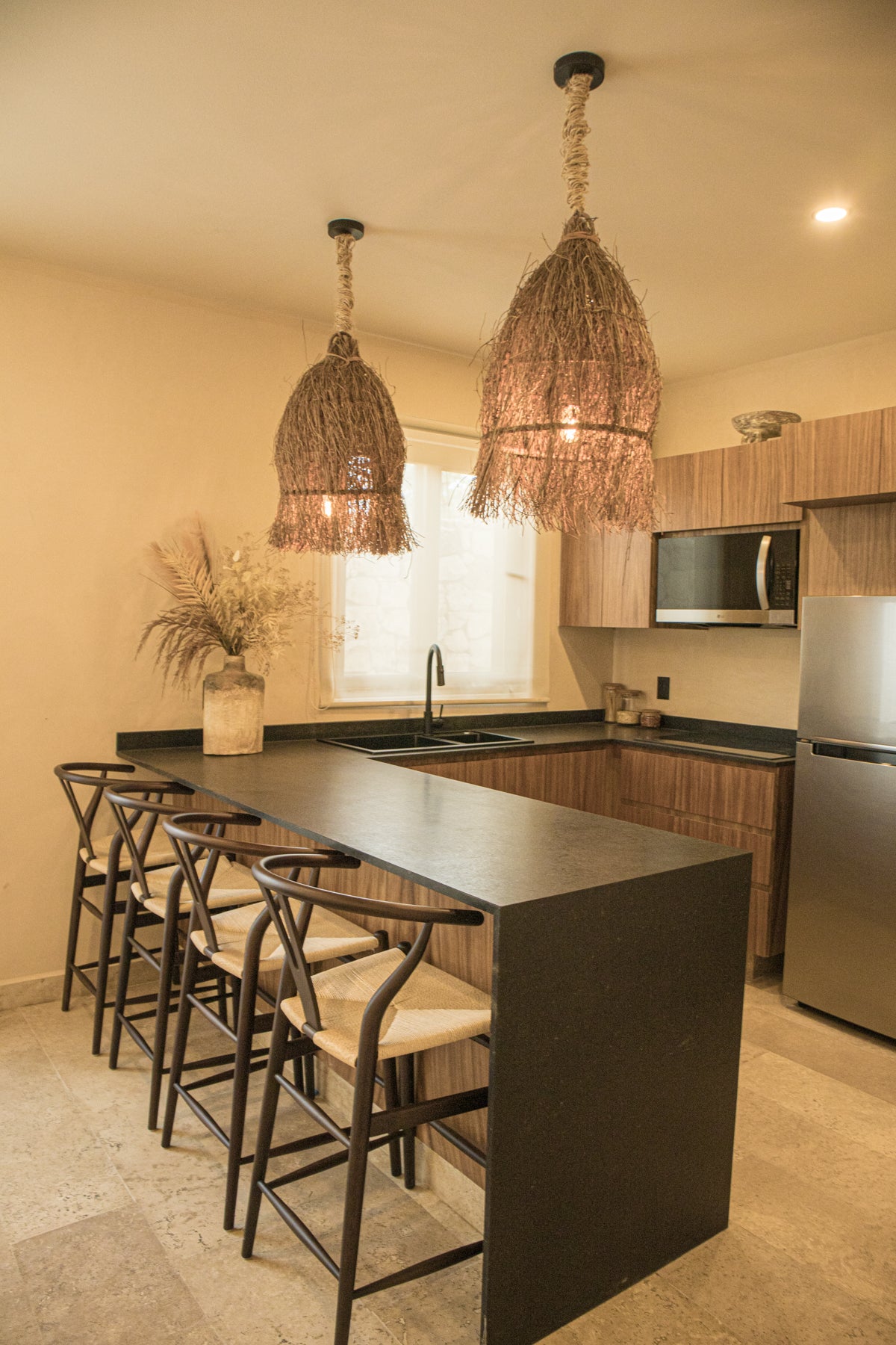 Cocina decorada con bancos para barra y lámparas de techo tejidas con yute