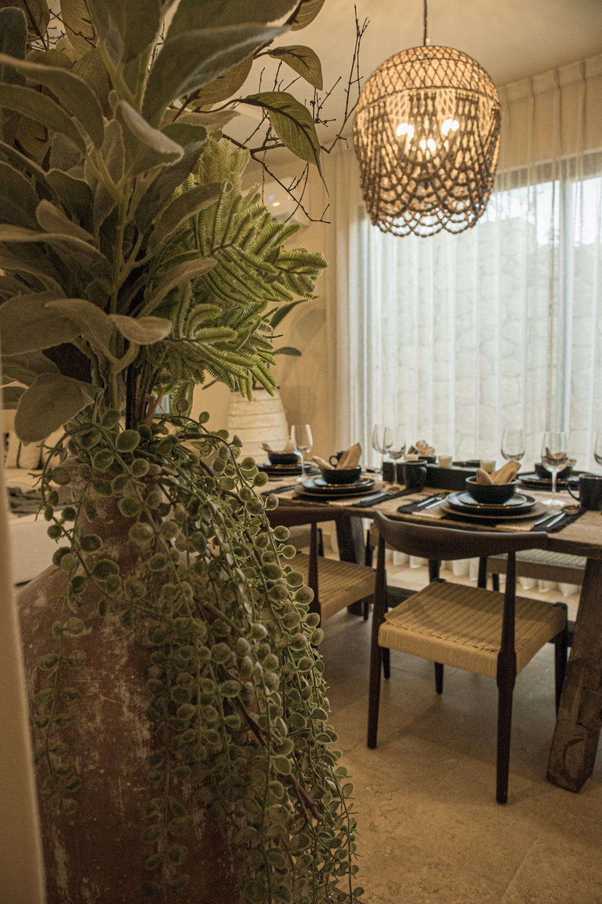 Comedor moderno en departamento en Tulum, con mesa de madera, sillas tejidas y lámparas de techo decorativas. Encuentra muebles en Prisma Muebles, mueblería en Tulum.