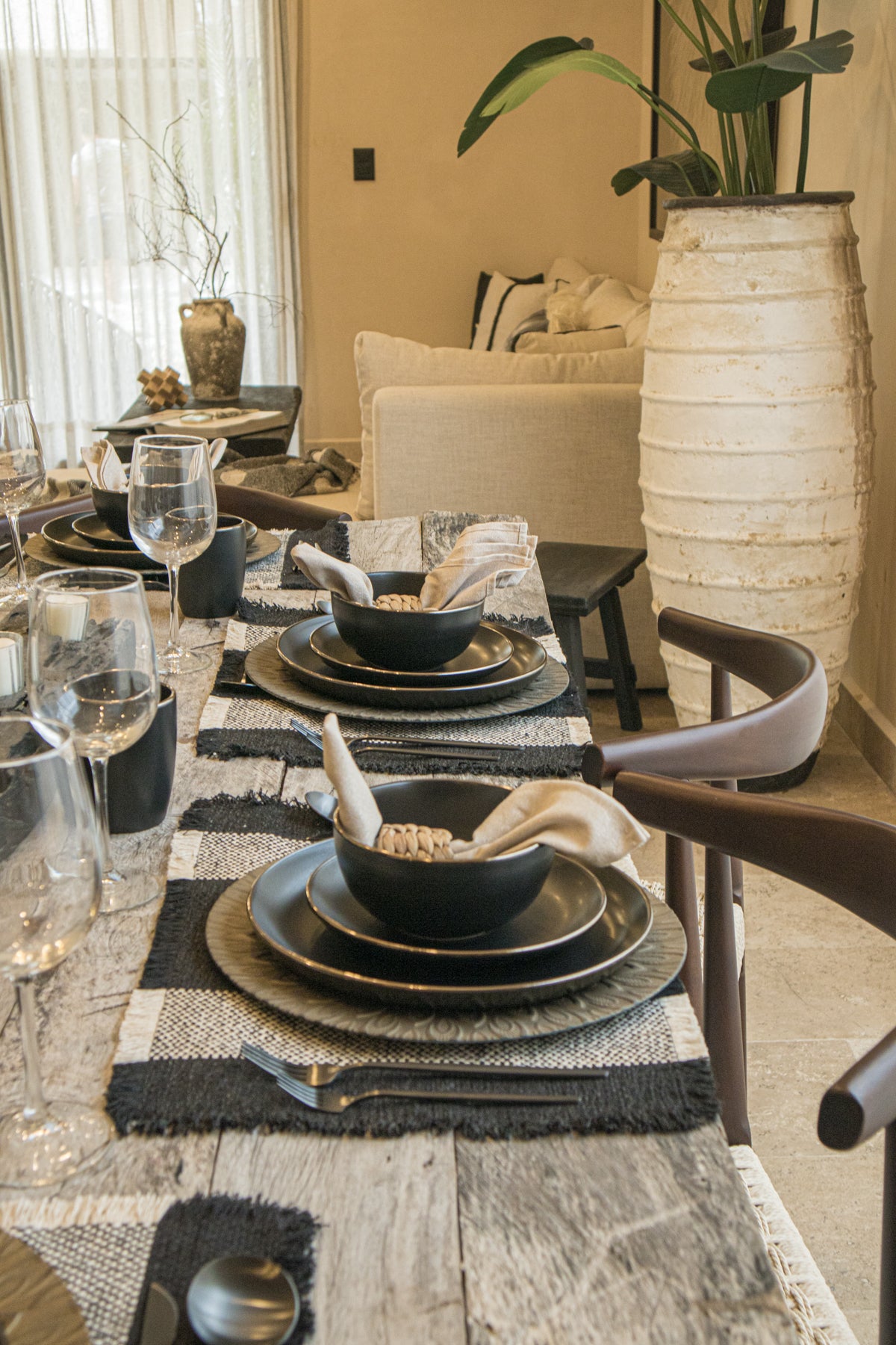 Elegante comedor con mesa de madera, sillas tejidas y una sala en l en tono neutro. Encuentra muebles de madera en Prisma Muebles Tulum.