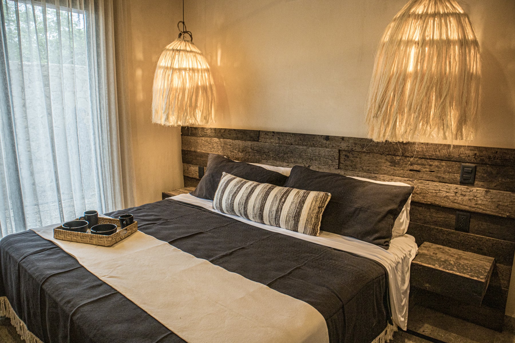 Vista isométrica de cama king size de madera con cojines decorativos, lámparas de techo tejidas con fibras naturales