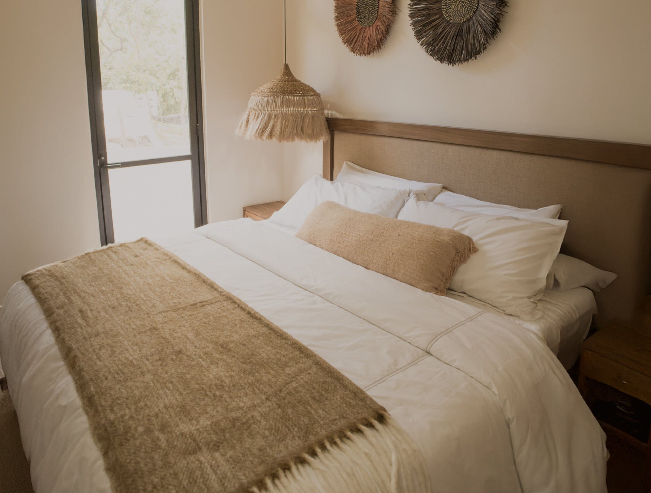 Recámara moderna con cama king size, cabecera tapizada, base de cama matrimonial en madera y lámpara colgante de fibras naturales. Ideal como inspiración de muebles para recámara en estilos cálidos y minimalistas.