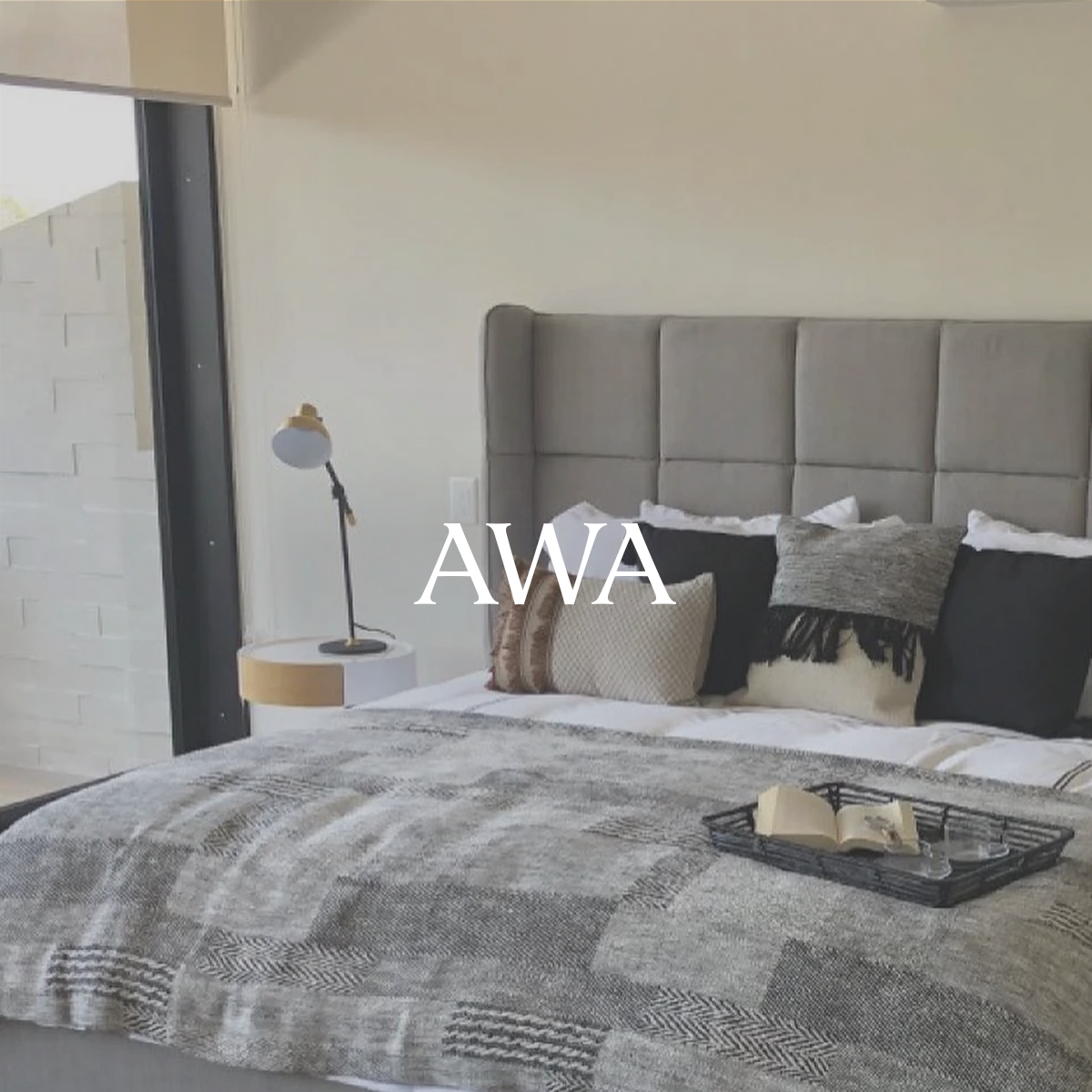 Diseño interior de una recámara matrimonial con cojines, buró de cama t lámpara.