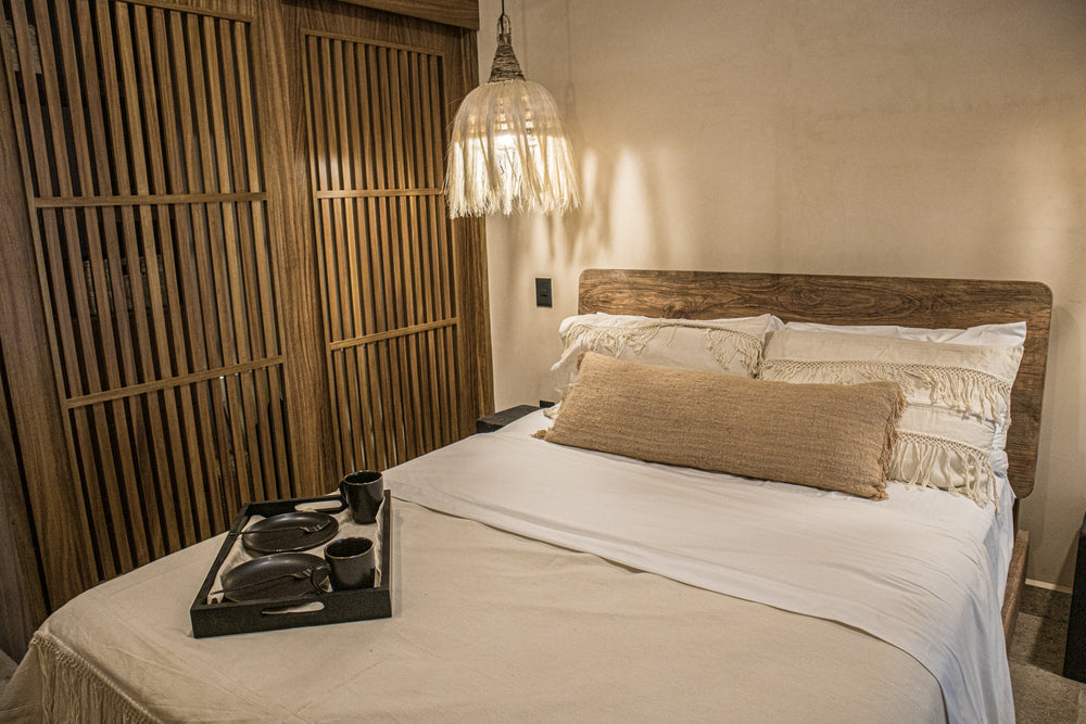 Vista isométrica de cama queen size de madera con cojines decorativos tejidos, edredón beige y lámparas de techo tejidas con fibras naturales 