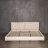 Cama king size tapizada en tela greige sobre base de madera maciza para recámara moderna